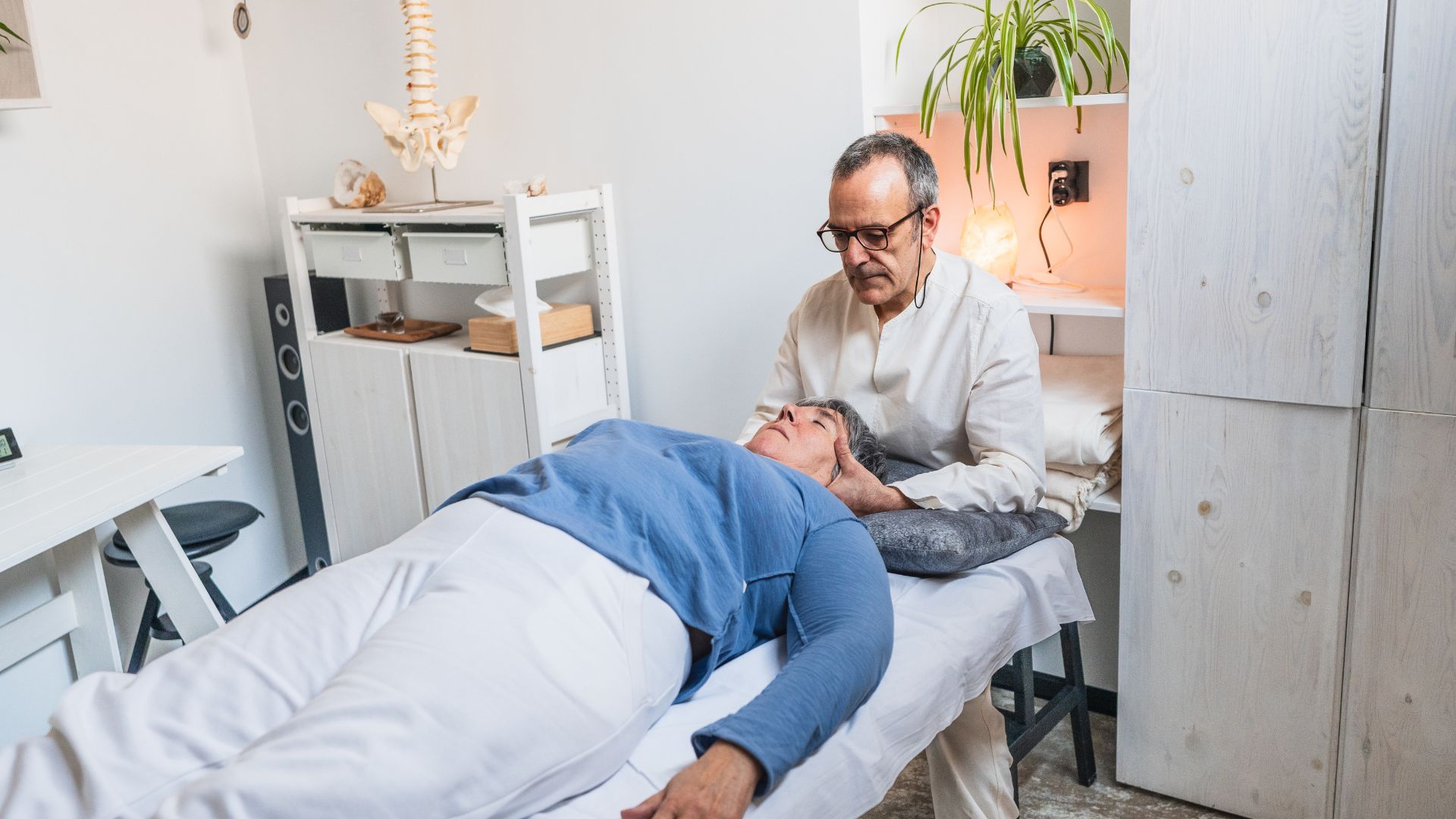 A chiropractor gently supporting a patient’s head during a neck adjustment in a calm, well-lit treatment room.