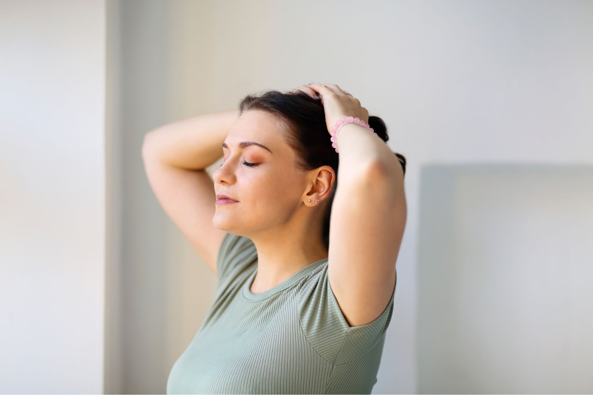 Design sem nome – 2025-10-03T203457.659 Profile of a woman with her eyes closed and hands on her head, against a bright background.