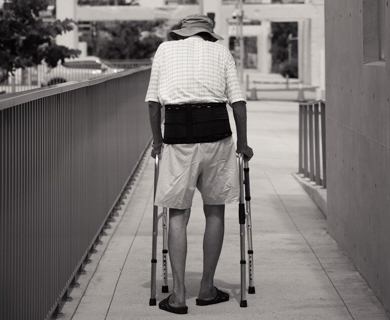 grayscale photo of man in black and white checked long sleeve shirt and black pants standing