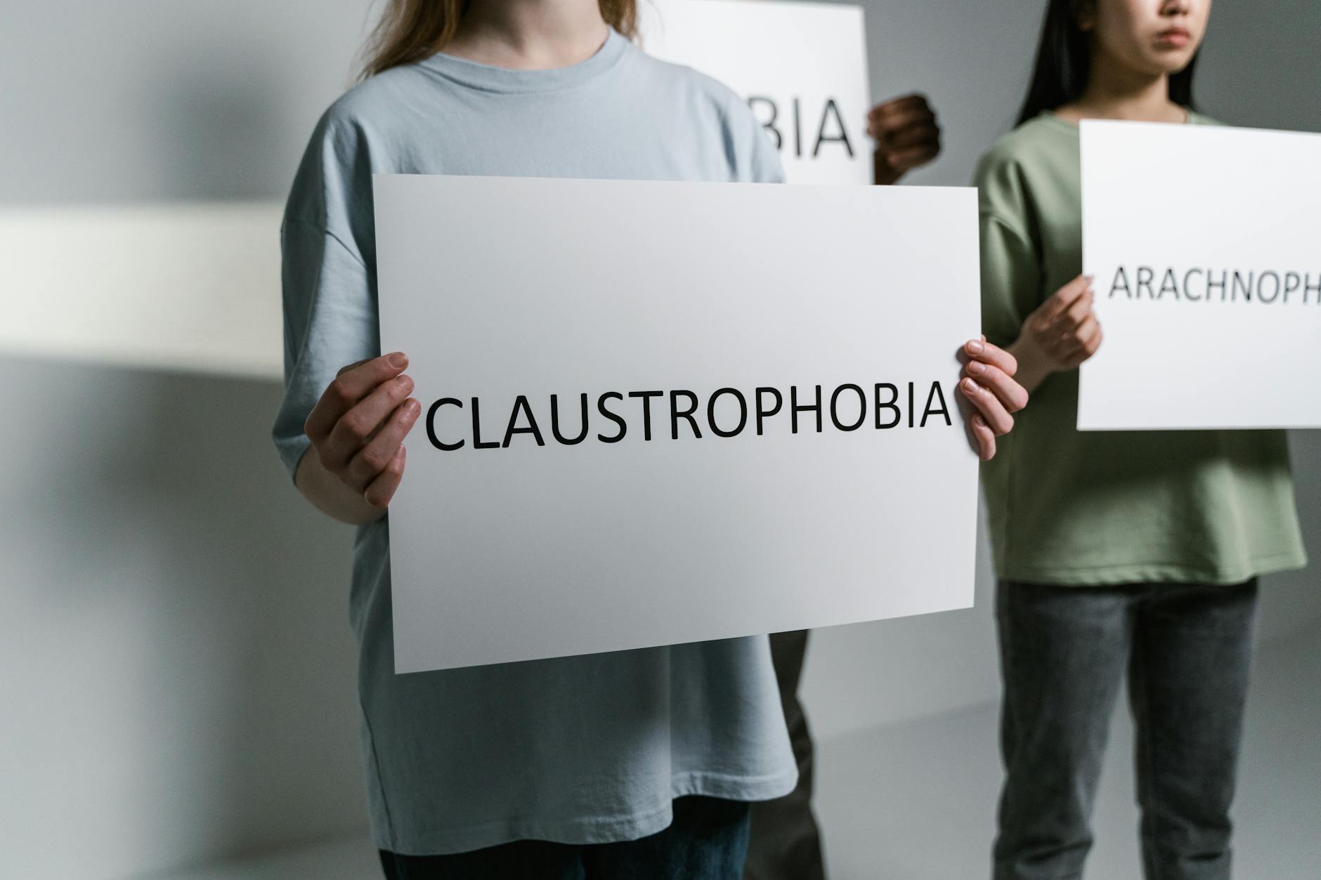 Group of individuals holding signs displaying phobia names in a neutral setting.