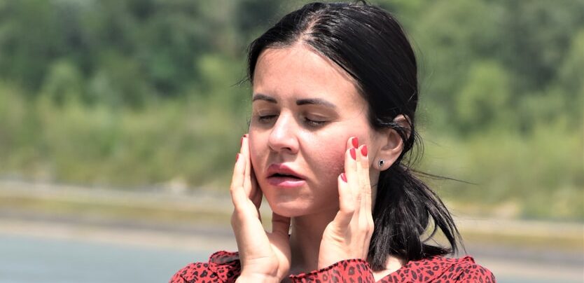 a woman in a red dress holding her hand to her face